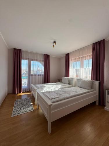 a large bedroom with two beds and windows at Hadnagy Étterem és Panzió in Lupeni