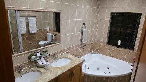 Un baño con dos lavabos y una bañera. en Golf & Tides Deluxe, en Mossel Bay