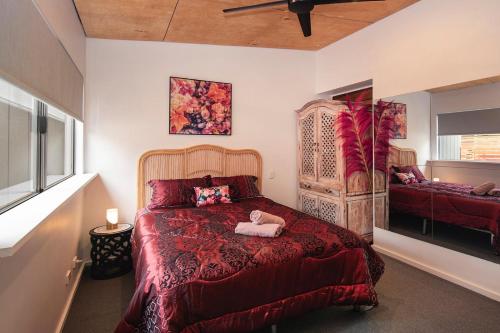 Un dormitorio con una cama roja con un animal de peluche. en La Boheme in the Treetops, en Margaret River Town