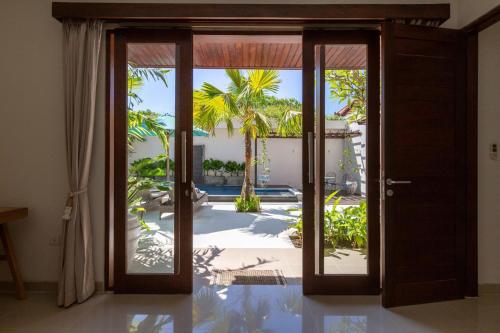 an open door to a patio with palm trees at Villa Stella - Tranquillity by the beach in Sanur