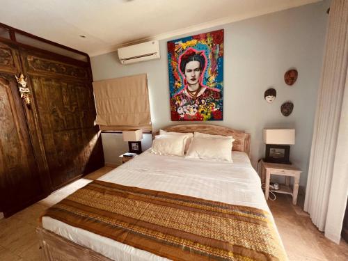 a bedroom with a bed with a painting on the wall at Villa Jasri Point - Beachfront Villa close to surf in Jasri