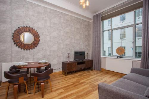 a living room with a table and chairs and a television at Stylish Merchant City Flat Glasgow in Glasgow