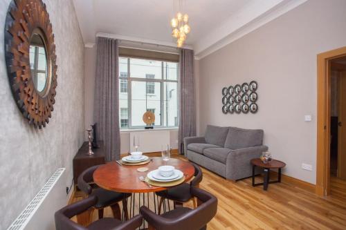 a living room with a table and chairs and a couch at Stylish Merchant City Flat Glasgow in Glasgow
