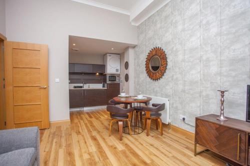 a living room with a table and chairs and a kitchen at Stylish Merchant City Flat Glasgow in Glasgow