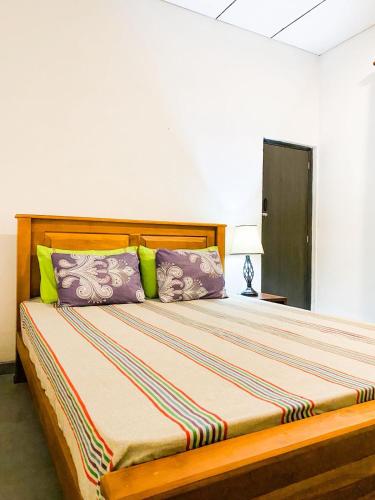 a bedroom with a bed with purple and green pillows at Haven Villa in Ahangama