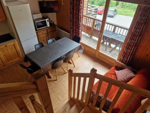 圣索林达尔沃Duplex avec piscine - Les Chalets de Saint Sorlin的带桌子和阳台的厨房和餐厅
