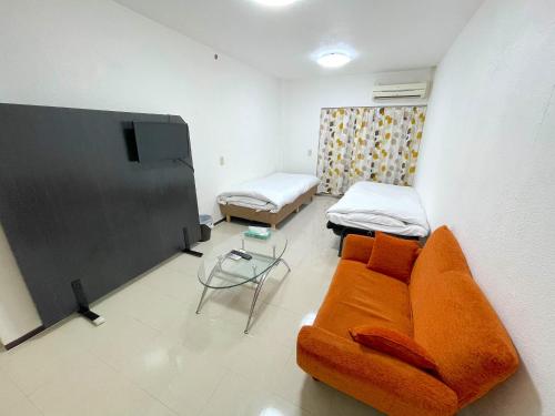 ein Wohnzimmer mit einem Sofa und 2 Betten in der Unterkunft ゲストハウスひわまり セルフチェックイン 瓦町すぐ in Takamatsu
