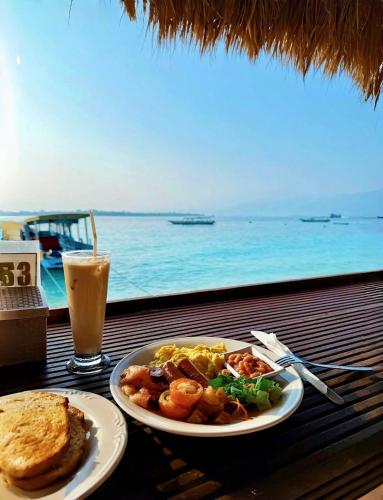 a table with a plate of food and a drink at Kura Kura Resort Gili Meno in Gili Meno
