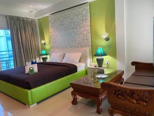 a bedroom with a bed with a green headboard at Access Inn Pattaya in Pattaya