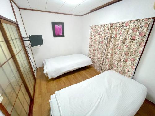 ein kleines Zimmer mit 2 Betten und einem Vorhang in der Unterkunft ゲストハウスひわまり セルフチェックイン 瓦町すぐ in Takamatsu