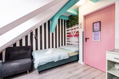 a room with a bed and a chair and a staircase at Vice City Hostel District 2 in Wrocław