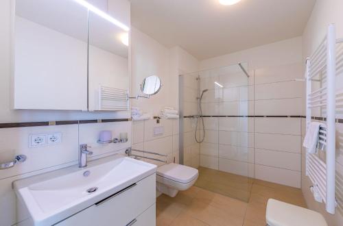 a white bathroom with a sink and a toilet at Sieglinde - Apartment in der Hafenresidenz mit Balkon & Wellness in Waren