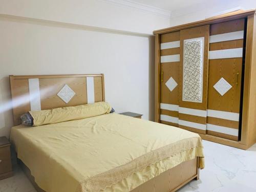 a bedroom with a bed with a wooden headboard at فيلا بقريه جرين بيتش 4 غرف وحمام سباحة خاص تشطيب السنه فرش مودرن in El Alamein