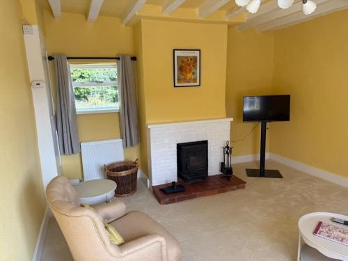 ein Wohnzimmer mit Kamin und Fernseher in der Unterkunft Pretty 2 Bedroom Cottage in Skirmett with Parking in Turville