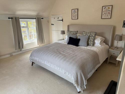 ein Schlafzimmer mit großem Bett und Fenster in der Unterkunft Pretty 2 Bedroom Cottage in Skirmett with Parking in Turville