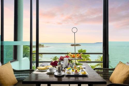 a table with food and a view of the ocean at Royal Wing Suites & Spa Pattaya in Pattaya South