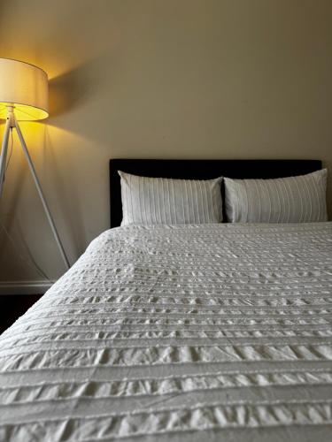 a bed with a white comforter and a lamp at Brand new bedroom next to train station in St Albans