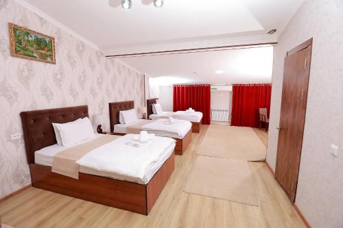2 camas en una habitación con cortinas rojas en Garden City, en Navoi