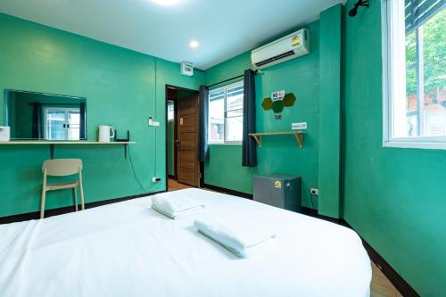 a green room with a bed with two pillows on it at GO INN The Giant Swing โก อินน์ เสาชิงช้า in Bangkok