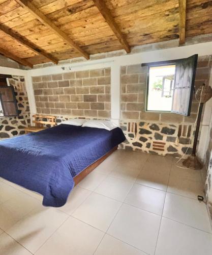 ein Schlafzimmer mit einem blauen Bett in einer Backsteinwand in der Unterkunft OYO Hotel Rincon De Texolo, Xico in Xico