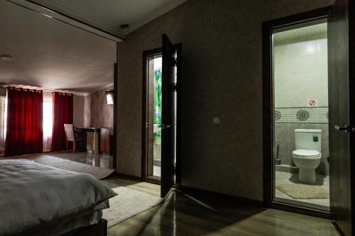 Un dormitorio con una cama y un baño con inodoro. en Garden City, en Navoi