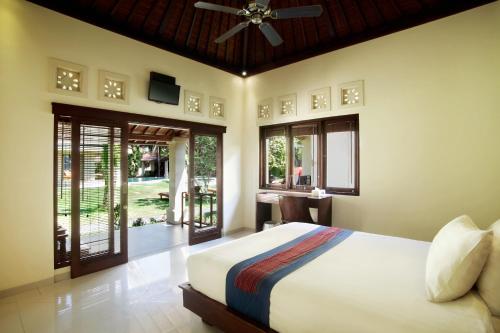 a bedroom with a bed with a ceiling fan at Puri Rinjani Bungalows in Kuta Lombok