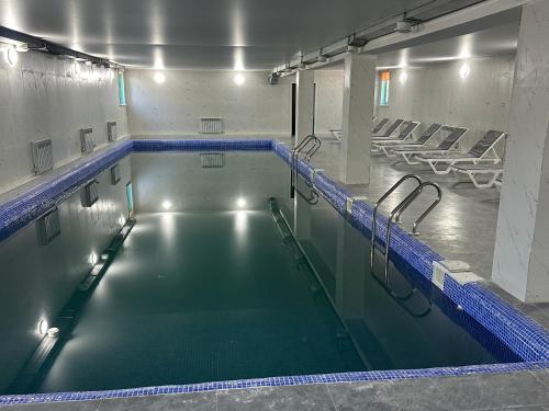 a large swimming pool with chairs in a building at Belon Garden Hotel in Prigorodnyy