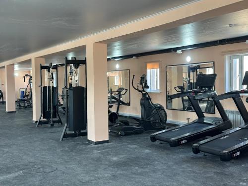 a gym with several treadmills and elliptical machines at Belon Garden Hotel in Prigorodnyy