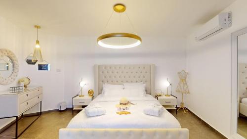 a bedroom with a large white bed and two night stands at זוהר בגליל-מיני וילה עם בריכה וג'קוזי בעין יעקב in ‘Ein Ya‘aqov