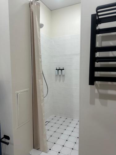 baño con ducha y suelo de baldosa blanca. en NovaHome Aktobe, en Aktobe