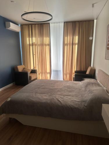 Un dormitorio con una cama grande y dos sillas. en NovaHome Aktobe, en Aktobe