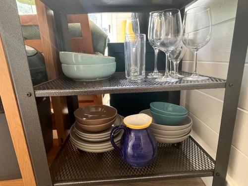 a shelf with wine glasses and plates and bowls at Caban y Castell in Moffat
