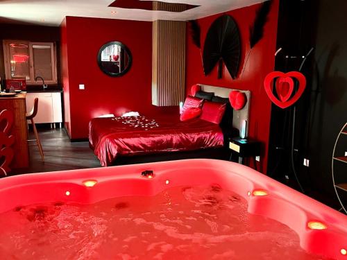 a red bathroom with a tub and a bed at Redroom, Spa, Sauna, cheminée, romantique pour 2 in Quimperlé