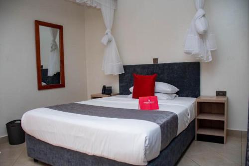 a bedroom with a large bed with a red pillow at Distinction Gardens in Siaya