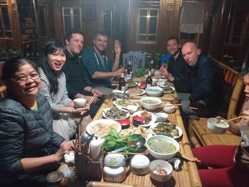 a group of people sitting around a table eating food at An' Home Mai Chau in Mai Chau