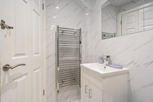 Un baño blanco con lavabo y espejo. en K Suites - Ashford Road, en Londres