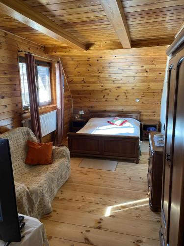 a bedroom with a bed and a couch in a cabin at Kampinówka in Tułowice