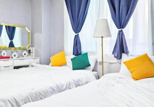 two beds in a room with blue curtains and a mirror at Aurora Stay in Pongsan-dong