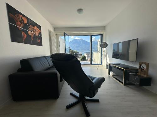 un salon avec une chaise noire et une télévision dans l'établissement Best View Appart Minusio, à Minusio