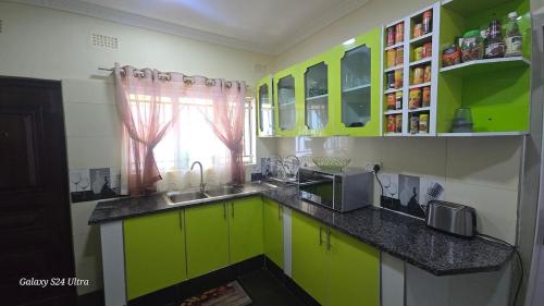 a kitchen with green cabinets and a sink and a window at FAMILY CLICK HOLMEs in Lilongwe
