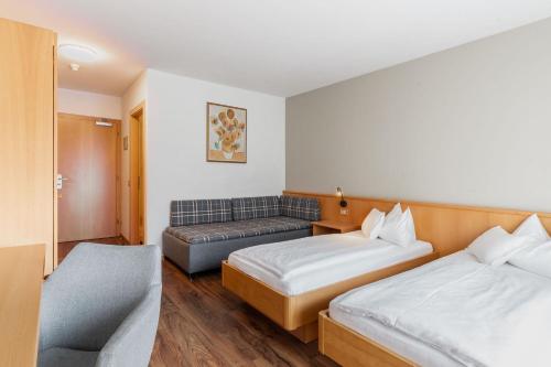 a hotel room with two beds and a couch at Hotel Brenner - Stop & Go in Vipiteno