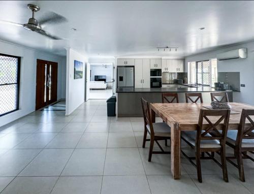 a kitchen and dining room with a wooden table and chairs at The Ranch 4brm,3bth,AC,Pool in Glenella