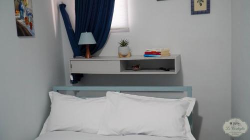 un letto con un cuscino bianco e uno scaffale sopra di Le Cortiglie Affittacamere a Piedimonte dʼAlife