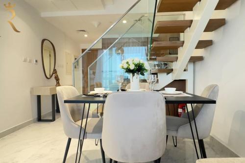 a dining room with a black table and white chairs at Luxe 2BR Oasis - Rooftop Elegance in Abu Dhabi