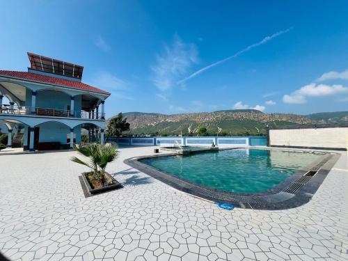 a swimming pool in front of a building with mountains in the background at harvest haven in Alwar