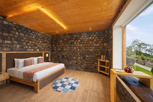 a bedroom with a bed and a stone wall at WelcomHeritage Arka Resort & Spa, Rishikesh in Bijni