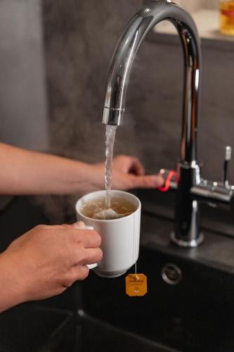eine Person trinkt Kaffee aus einer Tasse unter einem Waschbecken in der Unterkunft Hotel Brenner - Stop & Go in Sterzing