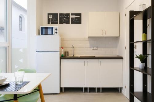 a kitchen with white cabinets and a white refrigerator at Suite by Hawkins Exterior 1B in Algeciras