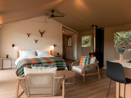 a bedroom with a bed and a living room at AfriCamps Klein Karoo in Oudtshoorn
