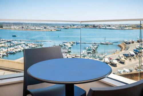 a table and chairs in a room with a view of a harbor at Jupiter Marina Hotel - Couples & Spa in Portimão